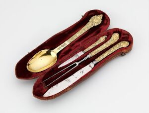  A luxurious decorative cutlery set, with a gold spoon and a silver knife resting in a maroon velvet-lined case, reflecting sophistication and meticulous craftsmanship. Artist name and title are unknown.