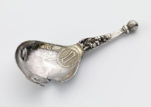  An intricate, antique silver spoon with textured bowl and detailed handle featuring gilded accents, artist unidentified.