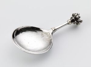  An elegantly designed silver spoon titled "Skje" by an unidentified artist, featuring a polished bowl with gilding and an engraved star on the handle, ending in an ornate cluster on the tip.