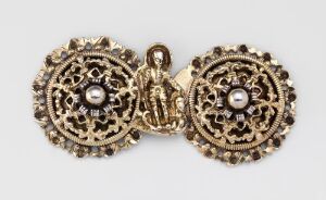  An antique gold-colored filigree brooch set with central pearls and a small figurative hinge linking the two pieces.