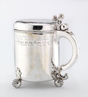 
 A silver drinking pitcher called "Drikkekanne" by Gjert Jørgensen Niemand, featuring hammered and engraved detailing with a reflective surface and ornate feet and handle.