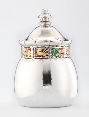  A polished silver pot with an intricate colored band design near the top, featuring a reflective surface, set against a muted background. Artist name and title are unknown.