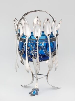  A sculpture featuring a cobalt blue vase with silver-white designs, encased in a metallic leaf-like structure with arcing branches and an ornate metallic base simulating natural forms.