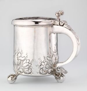  Silver drinking pitcher titled "Drikkekanne" by Johannes Johansen d.e. Reimers, featuring ornate floral engraving on a cylindrical body with a curved handle and three spherical feet.