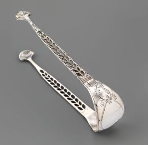  A silver sugar tong, "Sukkerklype," by Søren Gabriel Aamodt, with a polished finish, featuring detailed floral engravings and a pierced, lattice-like handle, set against a soft grey background.