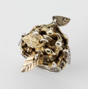  A meticulously crafted piece of gold-toned jewelry with intricate leaf designs, suggestive of a ring or wearable art, set against a light gray background. Artist name and title are unknown.