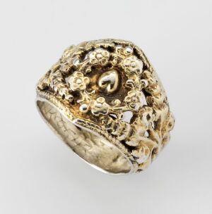  An intricately designed yellow-toned metal ring with a wide band that features raised floral-like and abstract patterns, suggesting a vintage or antique style.