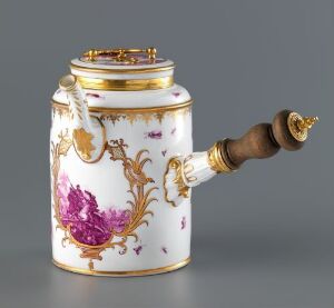  An antique porcelain tankard with gold accents and painted purple floral motifs, featuring a polished wooden handle with gold fixtures, on a soft grey background.