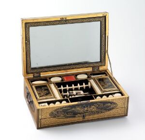  A golden-bronze antique vanity box with intricate engravings, open to reveal a mirror on the inside of the lid and various compartments housing black-topped containers on plush burgundy fabric.