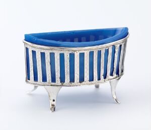  A small oval decorative object with an old-fashioned bathtub design, featuring cobalt blue and silver-white vertical stripes and ornate metal feet set against a white background. Artist name and title are unknown.