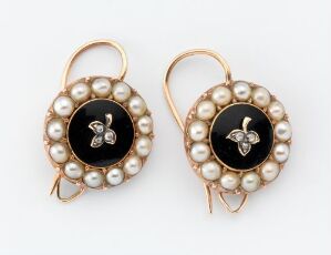  A pair of round earrings with a central black oval featuring a gold-colored fleur-de-lis symbol, surrounded by a ring of creamy pearls set in gold-colored metal, complete with french hook ear wires.