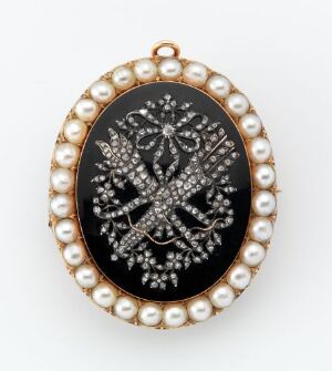  An oval-shaped vintage brooch or pendant with an outer band of pearls and a central black area adorned with a sparkling, symmetrical snowflake or starburst diamond pattern.