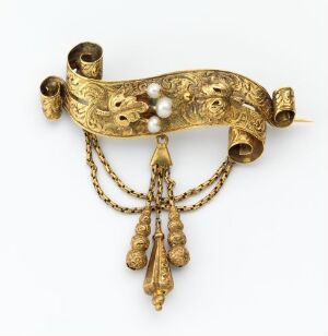  An exquisite gold brooch in a banner-like shape with floral embossing, featuring two sets of fine chains, granulated drop ornaments, and three pearls against a neutral background.