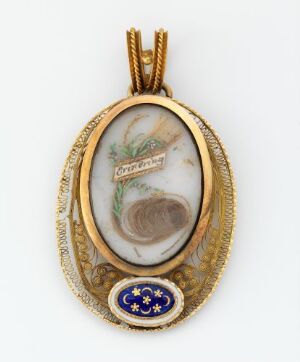  An oval gold-toned pendant featuring a central marbled insert with green foliage and woven hair, and a smaller blue enameled section decorated with golden stars at the bottom.