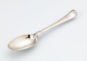  A polished silver spoon with a simple, elegant design rests on a light gray background, reflecting light on its smooth, lustrous surface.