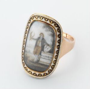  A vintage gold-tone ring with an oval bezel containing a miniature painting of a woman in antique attire holding an urn, standing beside a column, surrounded by a black and golden patterned border.