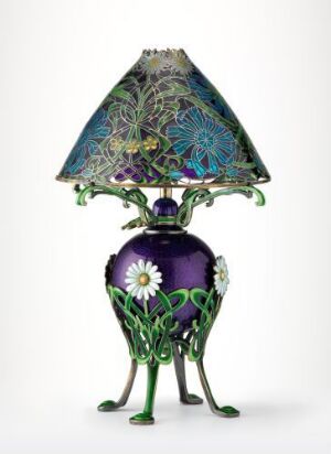  An Art Nouveau style lamp with a deep purple base adorned with a large white flower and green leaves, standing on three curved legs, and a blue-green, decorative patterned lampshade with floral motifs.