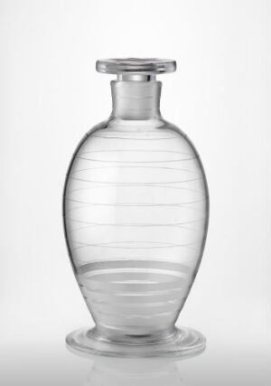  A translucent, blown and engraved glass bottle by artist Karen Jacobsen, with horizontal lines around the oval body, a flared neck, and a smooth, flat lip, presented against a plain, light background.