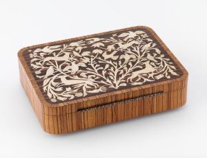  A small, rectangular wooden box with rounded corners and ribbed sides, featuring a detailed floral inlay in creamy off-white on the lid, set against a warm brown wood background.