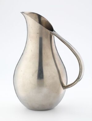  An image of a matte silver metal pitcher with a rounded body and a narrow neck, featuring a graceful handle and a dark vertical line down its center front, displayed against a plain background. Artist name and title remain unknown.