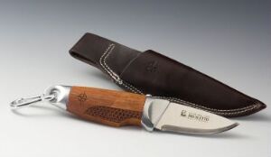  A stainless steel and wood knife by Permafrost with a dark brown leather sheath lies against a neutral grey background. The knife features a shiny blade with "H. Roselli" marked on the handle and a silver ring at the end, and the sheath is stitched with light-colored thread.