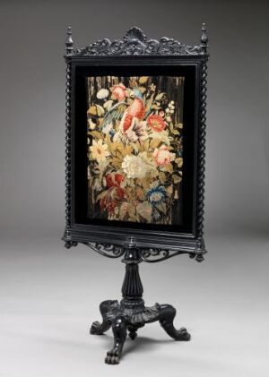  An antique, black ornate frame with a Baroque design, standing on an equally ornate black tripod stand with clawed feet. Inside the frame is a vibrant painting of a bouquet of assorted flowers with colors ranging from white, pink, red, orange, to yellow, set against a light gray background.