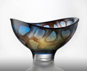  A decorative glass bowl by Orrefors Glasbruk A/B with an asymmetric rim, featuring a smoky base color with patches of vivid blue and warm golden-brown gradients, showcasing blown and multicolored glass craftsmanship.