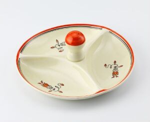  A divided serving dish from Egersunds Fayancefabrik with creamy white base color, a thick red rim, and delicate, nature-inspired decorations in each compartment. The central handle is a shiny tomato-red knob.