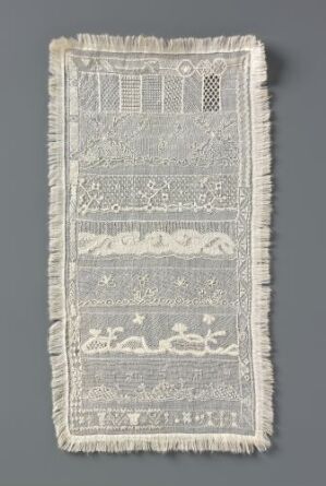  A historic white lace panel with intricate patterns, including geometric shapes, florals, and Arabic script, displayed against a grey background.