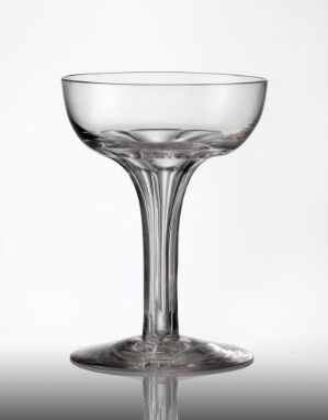  A transparent, blown, and facet-cut glass designed by Hadeland Glassverk, featuring a broad bowl atop a slender stem with a faceted knop, set against a light-gray background.