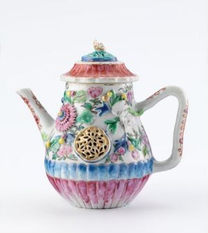  An intricately decorated teapot with a fluted body showing gradients from pink to blue to white, adorned with floral patterns and a bird, complete with a golden filigree spout and a red and gold finial on the lid.