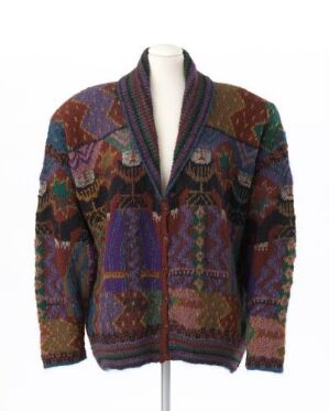  A hand-knitted cardigan titled 'Foolish Virgins' by Rowan Yarns, featuring rich purples, browns, oranges, and greens in complex geometric and organic patterns, with a shawl collar and housed on a mannequin.