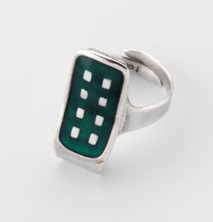  A silver ring designed by Grete Prytz Kittelsen featuring a geometric, enameled top in deep green, with two vertical columns of small rectangular indentations, balancing modern design with classic silverwork.