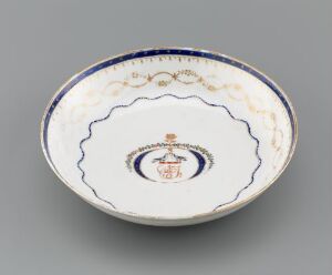  A decorative porcelain bowl with a white base and intricate blue, red, and gold design on the rim and a central emblem featuring similar colors.