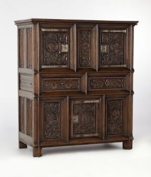  A cabinet by an unidentified artist, titled "Skap," crafted from oak with filling doors featuring low relief carving decoration, and iron hardware. The warm brown tones of the oak articulate the detailed carvings on the doors and drawers, highlighting the traditional design and craftsmanship.