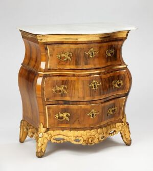  An unidentified artist's antique walnut-veneered kommode with gilded elements and carvings, featuring a bombé shape and topped with a marble slab.