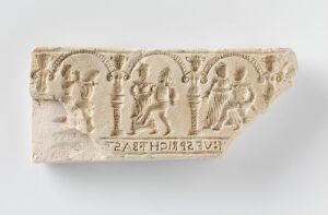  Fragment of beige earthenware titled "Bondedans" by an unknown artist, featuring a pressed relief of figures dancing within separate circular borders, with indistinct lettering along the bottom edge. The background is a light gray that gently contrasts with the clay's natural color.