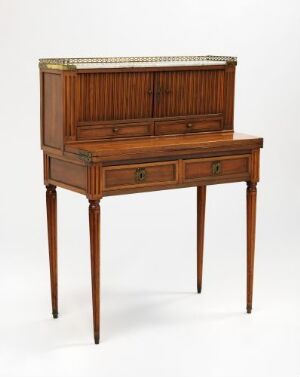  Antique wooden secretaire standing on tapered legs, with a gallery of turned spindles above small document slots, featuring a warm medium-brown finish and brass drawer pulls.