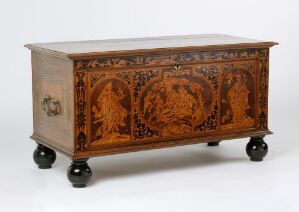  An oak chest titled "Kiste" by an unidentified artist, featuring skillful marquetry with foliage motifs in various shades of wood and metal fittings, on rolling spherical feet.