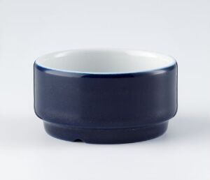  A porcelain bowl from the "Korulenserviset" series by Porsgrunds Porselænsfabrik AS, showcasing a glossy deep blue exterior and a bright white interior, exemplifying the clean and modern design of functional tableware.