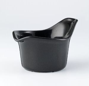  A glazed porcelain tableware piece in a deep black color with an asymmetrical and modern design by Tias Eckhoff, displayed against a plain background.