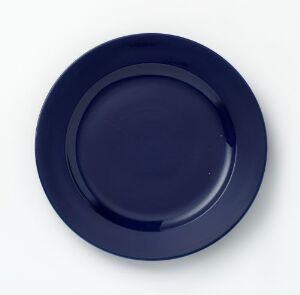  "Korulenserviset" by Porsgrunds Porselænsfabrik AS - A sleek, dark blue glazed porcelain plate with a simple, rounded rim, displayed against a light background.