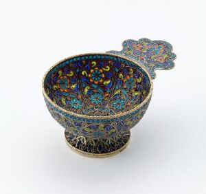  An intricately patterned bowl with a lid, featuring a dark blue background and a symmetrical colorful floral design with gold accents, on a white background.