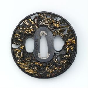  A circular Japanese tsuba (sword guard) with intricate gold designs on a black background and silver detailing around the central blade opening.