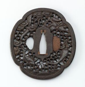  An antique, circular, dark brown, intricately patterned medallion-like metal object with an internal hinged piece, possibly used as a decorative handle or element, set against a light background.