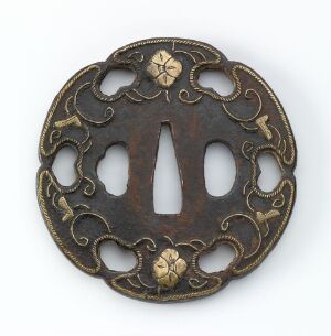  Antique Japanese tsuba (sword hand guard) with intricate scrollwork and floral motifs in dark brown and gold colors, featuring a central elongated-oval cutout.