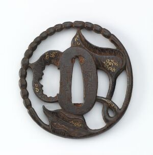  An antique, circular, openwork metal object with a dark brown patina and golden accents, featuring a symmetrical, organic design with an elongated central oval shape, suggesting it could be a piece of decorative art.