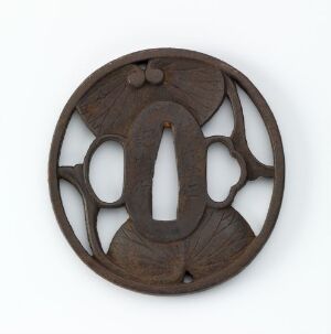  A round, dark brown wooden disc with an intricate symmetrical openwork design, featuring organic shapes and a central elongated aperture, set against a light gray background. Artistname and title are unknown.