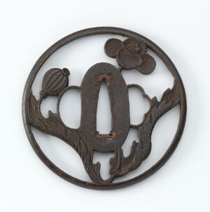  A circular, dark brown wooden carving with an elaborate design that resembles a stylized "A" surrounded by a flower and a ribbed oval motif, all against a plain background.