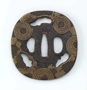 
 A Japanese tsuba (sword hand guard) with a dark, possibly iron base, featuring ornate golden circular motifs surrounding the central oval blade opening and four smaller sukashi (cut-out) openings.